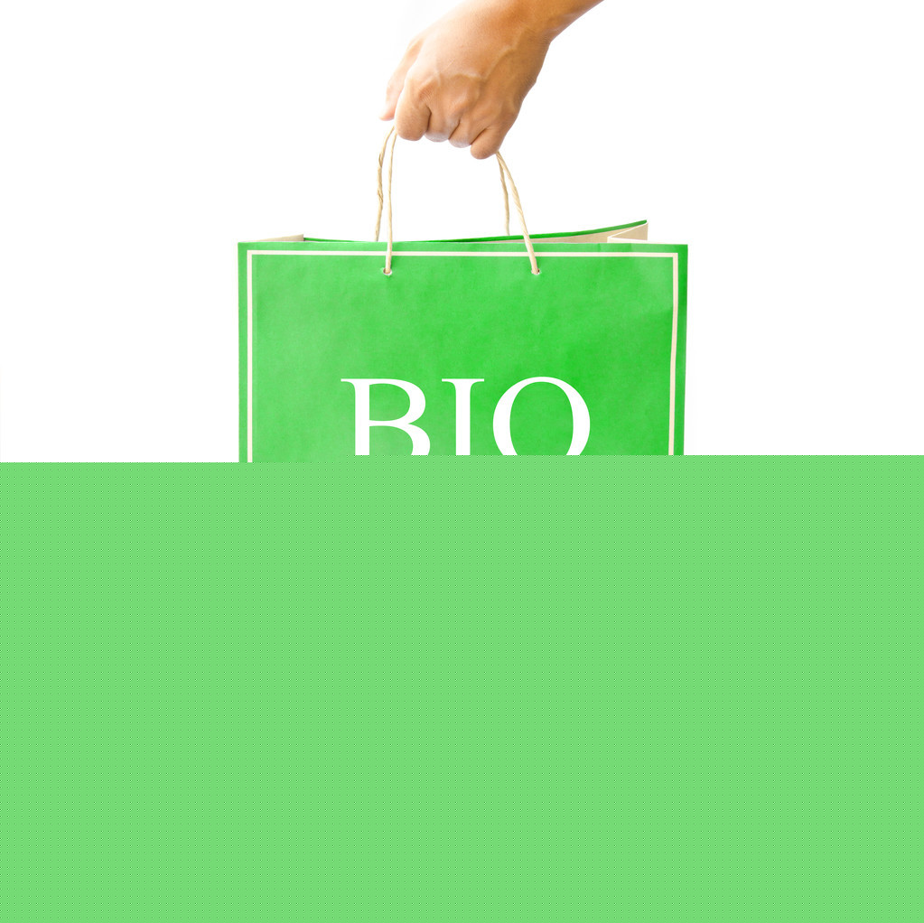 手保持綠色的紙購(gòu)物袋上反映出白色的地板